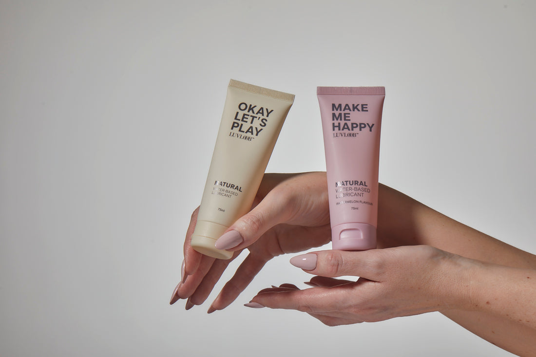 Hands holding two natural water-based intimate lubricants in minimalist packaging, highlighting products designed to enhance pleasure, intimacy, and self-care.”
